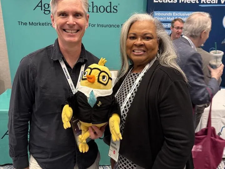 An agent holding the AgentMethods mascot at the booth